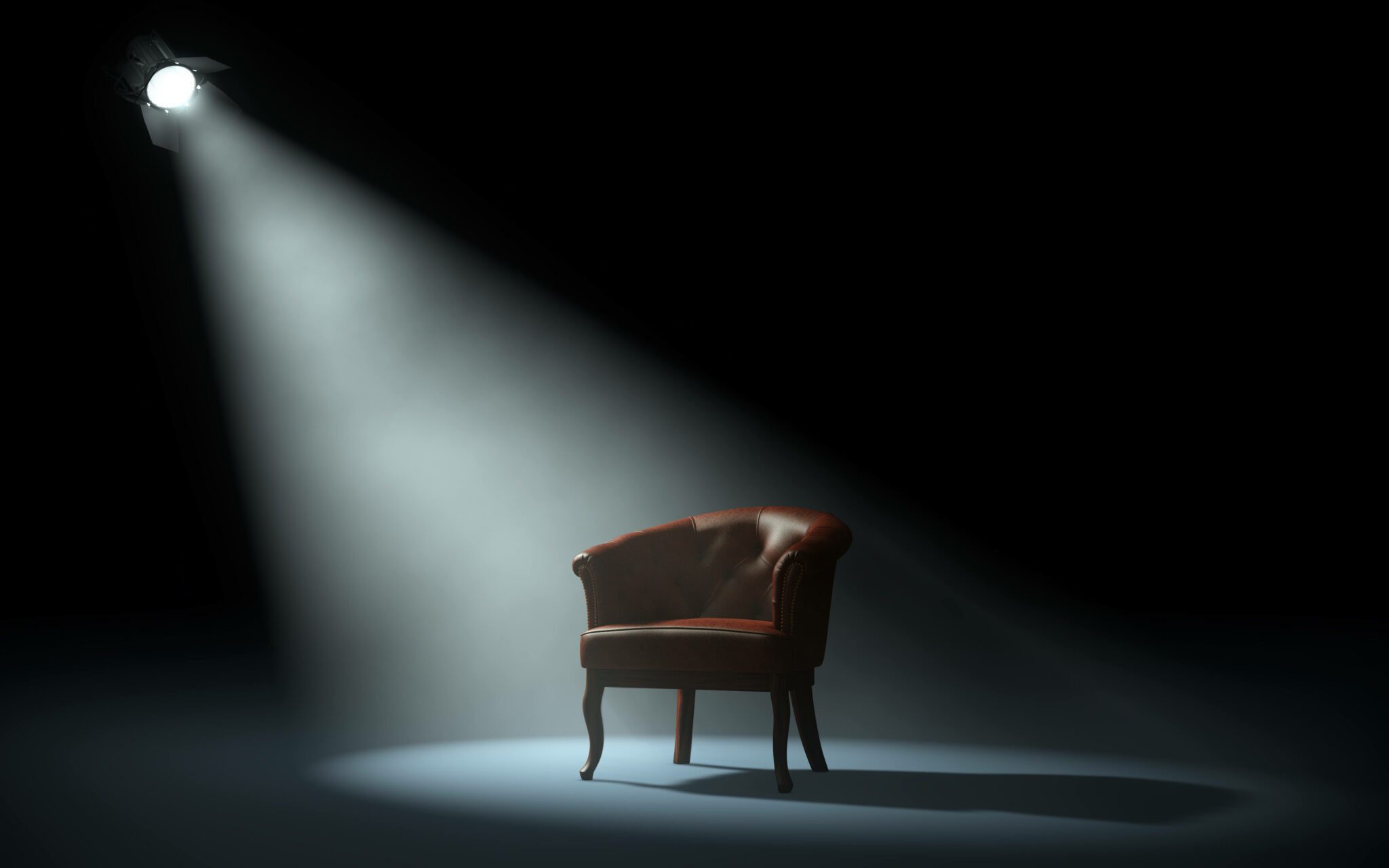 A black room with a spotlight shining on a chair.