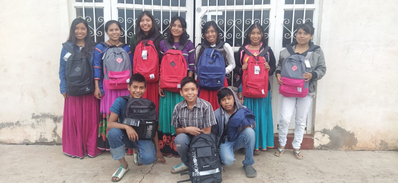 A smiling group of kids holding backpacks in South America