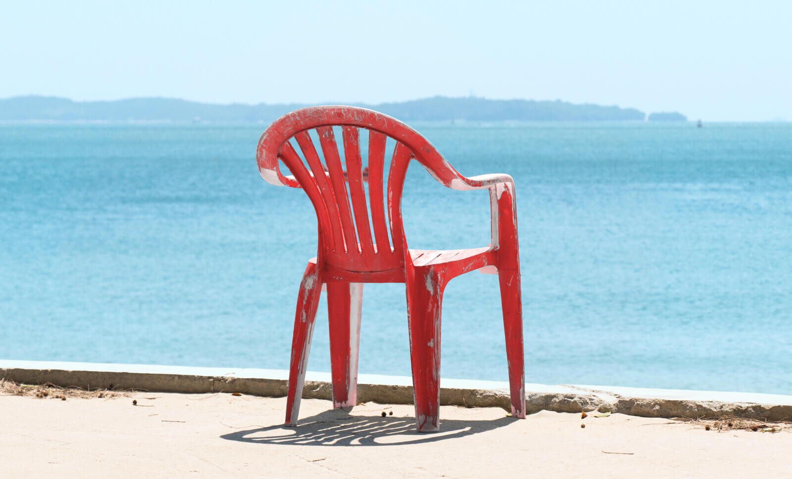 A red plastic chair is overlooking the water