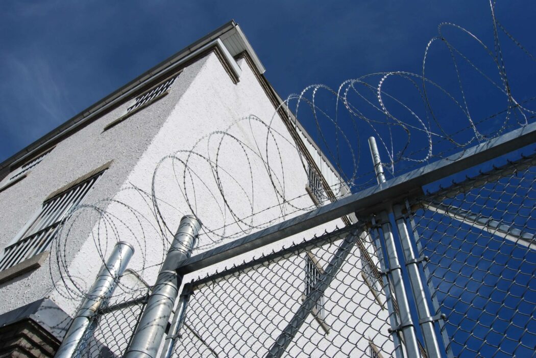 A barbed wire fence in front of a jail