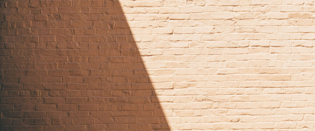 A brick wall with a shadow cast diagonally on it
