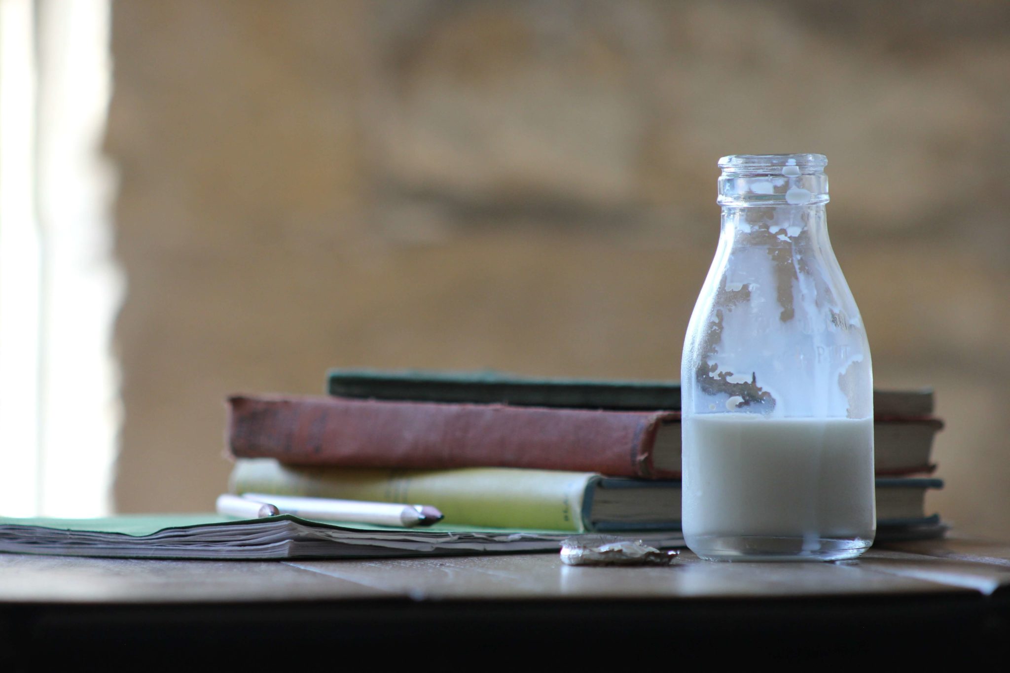 A half empty bottle of milk sitting on a table.