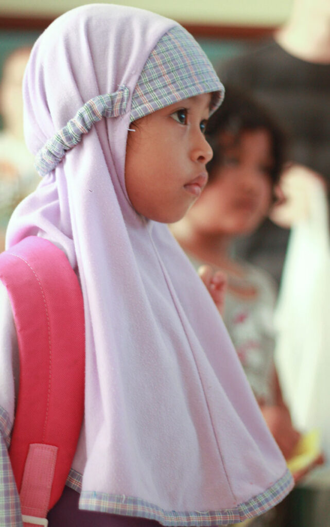 A young Sunda girl wearing an head scarf, looking off camera to the right.
