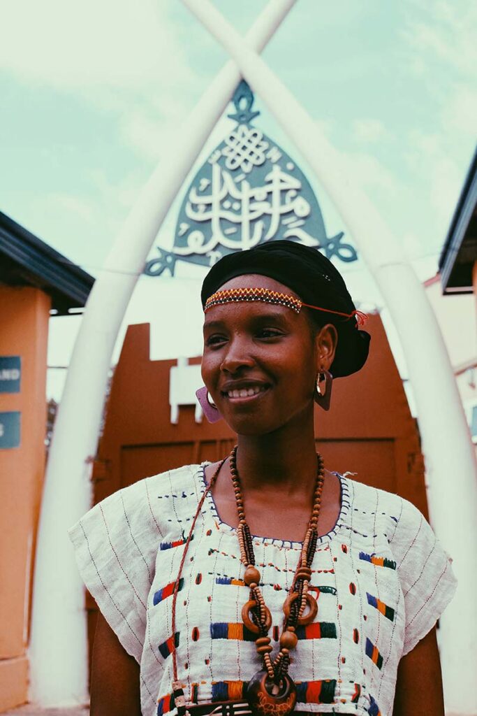 Image of a Fulani woman standing in traditional dress, looking off camera to the left.